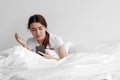 Confused shocked upset european young female received bad message, sits on white bed in bedroom interior