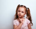 Confused smart cute kid girl thinking on blue studio background with empty copy space Closeup Royalty Free Stock Photo