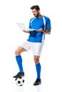 Confused soccer player using laptop and standing on ball