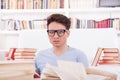 Confused student with glasses studying surrounded by books Royalty Free Stock Photo