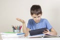 Confused,surprised child with tablet computer sitting at table with books notebooks Royalty Free Stock Photo