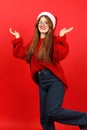 Confused and surprised young woman in santa hat on red background. New Year\'s fuss Royalty Free Stock Photo