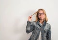 Confused teen girl in glasses holding hair looking skeptical