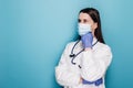 Confused and thoughtful female doctor, nurse in protective mask and gloves thinking, looking away indecisive Royalty Free Stock Photo