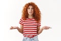 Confused uncertain stylish beautiful redhead curly girlfriend shrugging dismay puzzled holding smartphone hands spread Royalty Free Stock Photo