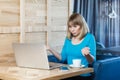 Confused uncertain young woman working on laptop, shrugging shoulders, looks doubtful and puzzled.