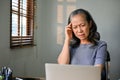 Confused Asian-aged woman having a problem with her internet connection on her laptop Royalty Free Stock Photo