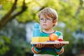 Confused upset little preschool boy with books, apple and drink bottle on his first day to elementary school. Sad child Royalty Free Stock Photo