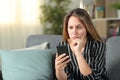 Confused woman checking mobile phone content at home