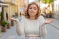 Confused woman feeling embarrassed about ambiguous question having doubts no idea in city street