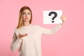 Confused woman holding question mark sign on background Royalty Free Stock Photo