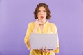 Confused woman isolated over purple wall background using laptop computer. Royalty Free Stock Photo