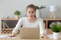 Confused woman looking at laptop screen, doing difficult computer work