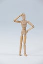 Confused wooden figurine standing with hand on head