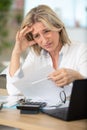 confused worried woman looks through papers sitting at home