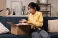 Confused young Asian woman unpacking wrong parcel, delivery mistake Royalty Free Stock Photo