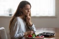 Confused young lady hesitating what to choose, salad or sweets Royalty Free Stock Photo