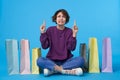 Confused young pretty dark haired curly female with short haircut keeping her index fingers raised while looking upwards with Royalty Free Stock Photo