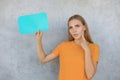 Confused young woman holding empty speech bubble  over grey background Royalty Free Stock Photo