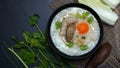 Congee with minced pork and boiled egg in black bowl on a dark background Royalty Free Stock Photo