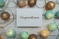 Congrats text on paper card with LED cotton balls top view on wooden background