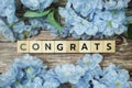 Congrats alphabet letter with Blooming flower on wooden background