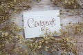 Congrats text on paper card with flower decoration on wooden background