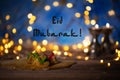 Congratulation: Eid Mubarak! Arabic sweets on a wooden surface.