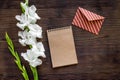 Congratulation. Envelope and notebook near flower gladiolus on wooden table top view copyspace mockup