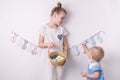 Congratulations on happy Easter: the girl is holding a basket with painted eggs by the white wall. Royalty Free Stock Photo