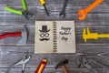 Congratulations Happy Fathers Day old notebook is surrounded by a toy tool on a rustic background.