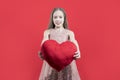 Congratulations on the holiday. A cute girl holding a red heart in her hands on a red background. Valentine`s day. Love. Royalty Free Stock Photo