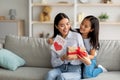 Congratulations. Loving asian daughter greeting surprised mom with Mother& x27;s Day, giving her handmade card and gift box Royalty Free Stock Photo