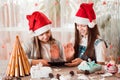 Congratulations in quarantine. Girls in Christmas decorations greet and communicate with their families through a tablet Royalty Free Stock Photo