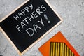 Happy fathers day on chalk board with orange diary and yellow tie on gray concrete background