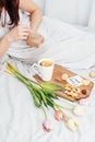 Congratulations to your beloved woman on Valentine`s Day. Breakfast in bed for a girl in a nightgown. Flowers and a gift for Royalty Free Stock Photo