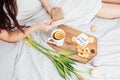 Congratulations to your beloved woman on Valentine`s Day. Breakfast in bed for a girl in a nightgown. Flowers and a gift for Royalty Free Stock Photo