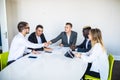 Congratulations. Two confident businessmen handshaking and smiling while sitting at the table together with their colleagues Royalty Free Stock Photo