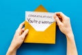 Congratulations You`re a winner. Hands holding envelope with letter. Blue background top view