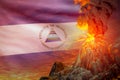conical volcano blast eruption at night with explosion on Nicaragua flag background, problems of natural disaster and volcanic