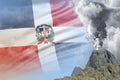 Conical volcano blast eruption at day time with white smoke on Dominican Republic flag background, problems of natural disaster