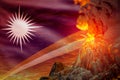 Conical volcano eruption at night with explosion on Marshall Islands flag background, suffer from natural disaster and volcanic