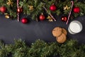 Coniferous Christmas garland decorated with red balls and golden bells with caramel canes at the top and bottom of the black table Royalty Free Stock Photo