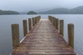 Coniston Water lake in Rigg Wood. Wooden pier in a quiet foggy day Royalty Free Stock Photo