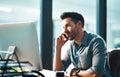 Connect and stay in the business loop. a young businessman using a mobile phone and computer at his desk in a modern Royalty Free Stock Photo