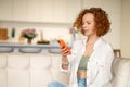 Cute ginger woman with a smartphone in hands