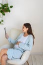 Cute young pregnant woman with a device in hand