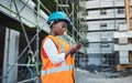 Connected with the field team right from her phone. a young woman using a smartphone while working at a construction Royalty Free Stock Photo