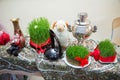 Novruz holiday background . Connected with a red ribbon green semeni . Samovar. Sheep puppet