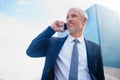 Connected to his business on the go. a businessman answering his phone while walking to his office in the city. Royalty Free Stock Photo